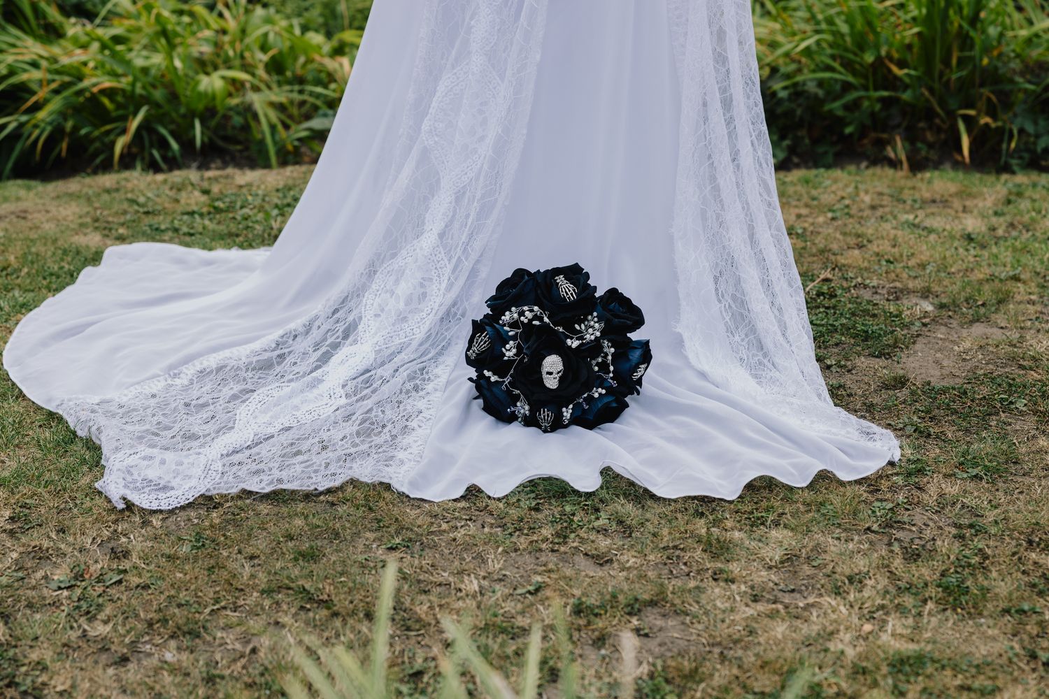 Black bouquet with a skull detail resting on the bride's dress train, rock themed wedding at the Valley Hotel, Ironbridge